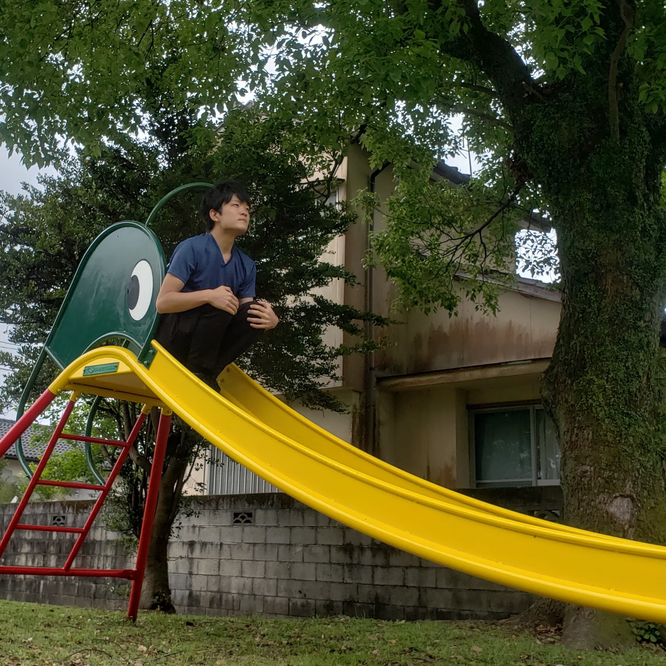 滑り台の上で膝を抱えて空を見上げています。